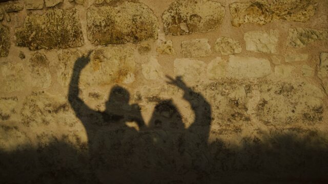 Shadows of two people are cast on a wall.