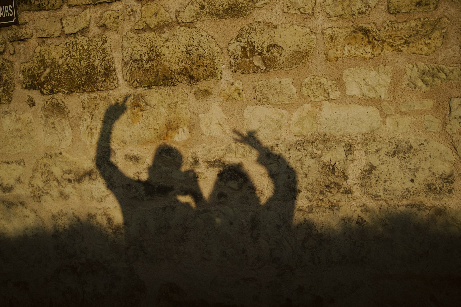 Shadows of two people are cast on a wall.