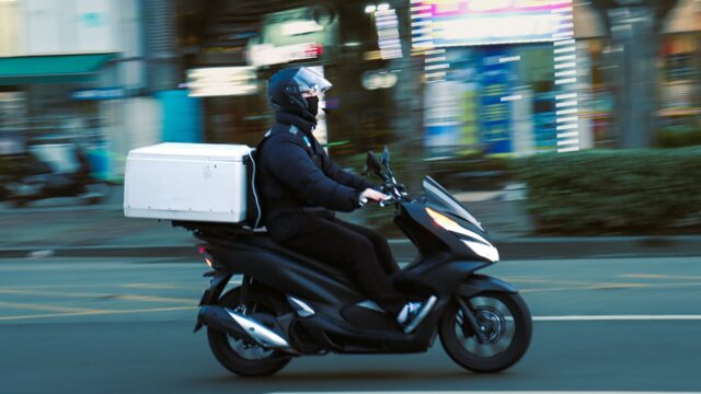a man riding a scooter with a box on the back of it